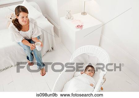 Mother looking at baby in bassinet View Large Photo Image Stock Image - Mother looking at baby in bassinet. Fotosearch