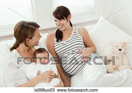 Stock Image - Mother with baby girl and pregnant friend. Fotosearch