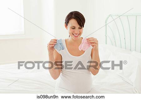 Pregnant woman looking at blue and pink baby socks View Large Photo Image Picture - Pregnant woman looking at blue and pink baby socks. Fotosearch