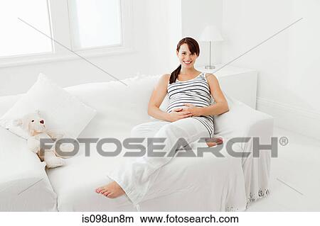 Pregnant woman sitting on sofa View Large Photo Image Picture - Pregnant woman sitting on sofa. Fotosearch