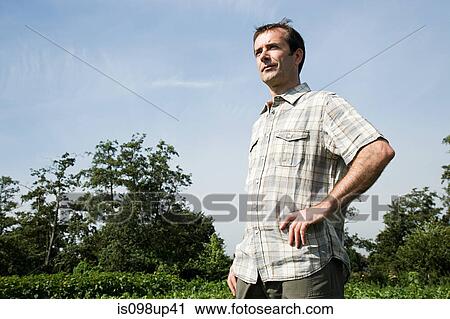 Stock Image - Farmer standing in field. Fotosearch