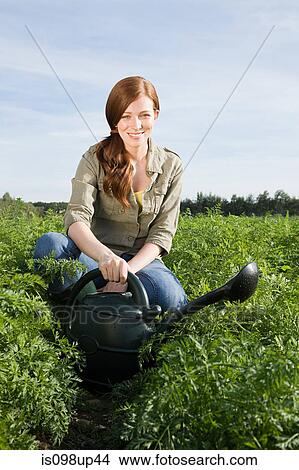 Woman watering crop in field with watering can View Large Photo Image Picture - Woman watering crop in field with watering can. Fotosearch
