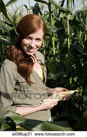 Stock Image - Young woman holding corn cob. Fotosearch