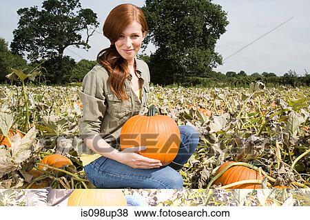 Young woman holding pumpkin View Large Photo Image Stock Photo - Young woman holding pumpkin. Fotosearch