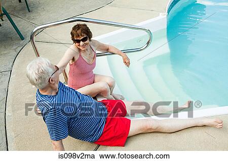 Stock Image - Senior couple by swimming pool. Fotosearch
