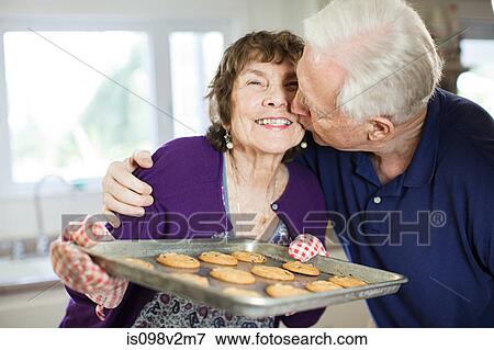Senior couple kissing with home baked cookies View Large Photo Image Stock Photo - Senior couple kissing with home baked cookies. Fotosearch