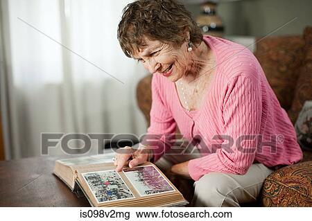 Senior woman looking at family album View Large Photo Image Stock Image - Senior woman looking at family album. Fotosearch