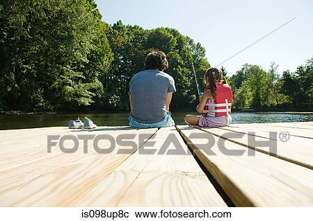 Stock Image - Father and daughter fishing from jetty. Fotosearch