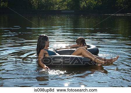 Stock Image - Mother and daughter in lake on inflatable rings. Fotosearch