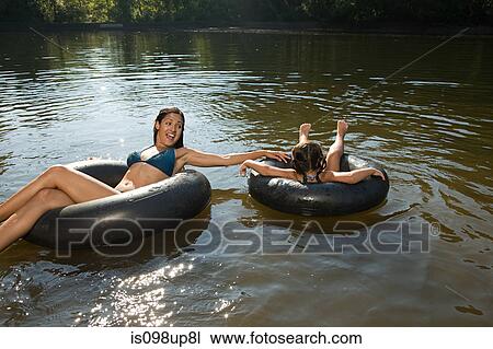 Stock Image - Mother and daughter in lake on inflatable rings. Fotosearch