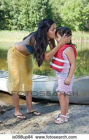 Mother kissing daughter by rowboat View Large Photo Image Picture - Mother kissing daughter by rowboat. Fotosearch