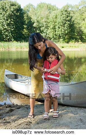 Mother putting lifejacket on daughter View Large Photo Image Stock Photo - Mother putting lifejacket on daughter. Fotosearch