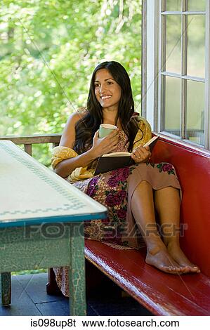 Young woman relaxing with book and hot drink View Large Photo Image Stock Photograph - Young woman relaxing with book and hot drink. Fotosearch