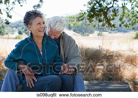 Happy couple sitting on picnic table View Large Photo Image Stock Photograph - Happy couple sitting on picnic table. Fotosearch