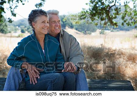 Stock Photography - Happy couple sitting on picnic table. Fotosearch