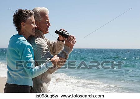 Mature couple at the beach with binoculars View Large Photo Image Stock Photo - Mature couple at the beach with binoculars. Fotosearch