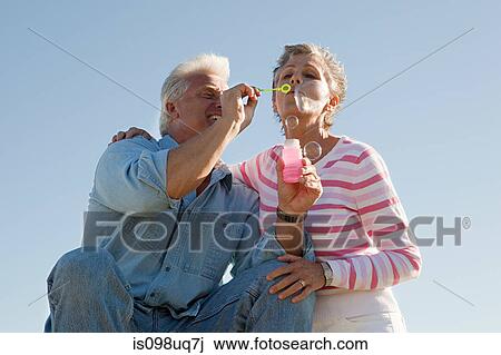 Stock Image - Mature couple blowing bubbles. Fotosearch