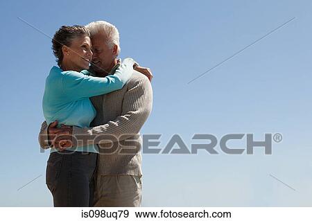 Mature couple hugging against blue sky View Large Photo Image Stock Photo - Mature couple hugging against blue sky. Fotosearch
