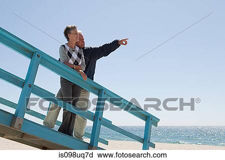 Stock Image - Mature couple on beach walkway. Fotosearch