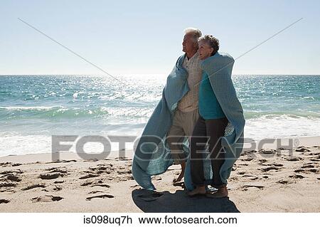 Mature couple on beach wrapped in blanket View Large Photo Image Stock Image - Mature couple on beach wrapped in blanket. Fotosearch