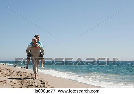 Mature couple piggybacking on beach View Large Photo Image Stock Photo - Mature couple piggybacking on beach. Fotosearch