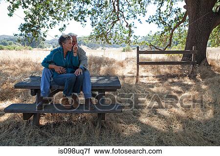 Mature couple sitting on picnic table View Large Photo Image Stock Image - Mature couple sitting on picnic table. Fotosearch