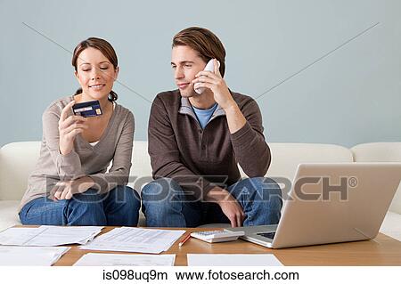 Picture - Young couple using computer and doing paperwork. Fotosearch