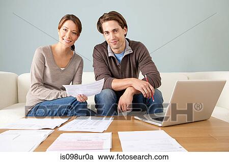Stock Image - Young couple using computer and doing paperwork. Fotosearch