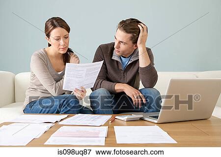 Stock Photo - Young couple using computer and doing paperwork. Fotosearch