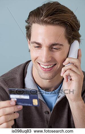 Young man on the phone with credit card View Large Photo Image Stock Image - Young man on the phone with credit card. Fotosearch