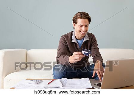 Young man with credit card using laptop View Large Photo Image Picture - Young man with credit card using laptop. Fotosearch
