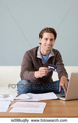 Young man with credit card using laptop View Large Photo Image Stock Photo - Young man with credit card using laptop. Fotosearch
