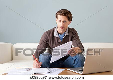 Young man with paperwork using laptop View Large Photo Image Stock Photo - Young man with paperwork using laptop. Fotosearch