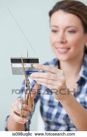 Stock Image - Young woman cutting credit card. Fotosearch