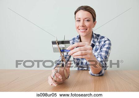 Stock Photography - Young woman cutting credit card. Fotosearch