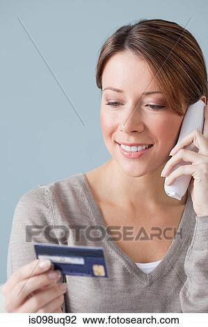 Stock Image - Young woman on the phone with credit card. Fotosearch