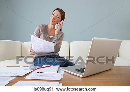 Stock Image - Young woman on the phone with laptop. Fotosearch
