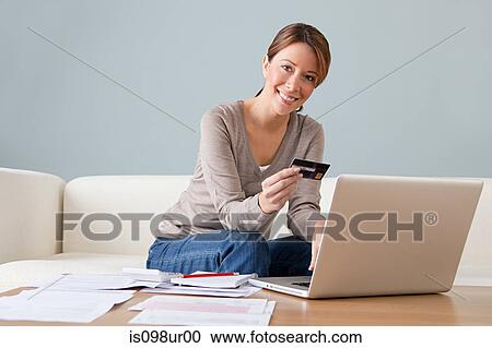 Stock Image - Young woman with credit card using laptop. Fotosearch