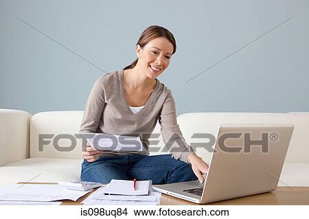 Young woman with paperwork using laptop View Large Photo Image Picture - Young woman with paperwork using laptop. Fotosearch