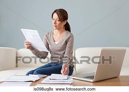 Young woman with paperwork using laptop View Large Photo Image Stock Photo - Young woman with paperwork using laptop. Fotosearch