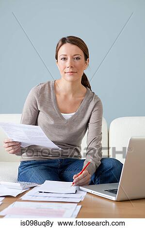 Young woman with paperwork using laptop View Large Photo Image Stock Photo - Young woman with paperwork using laptop. Fotosearch