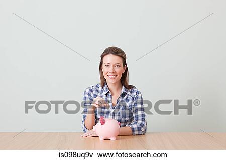 Stock Photo - Young woman with piggy bank. Fotosearch