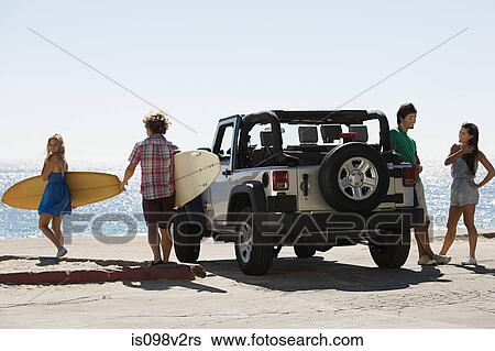 Stock Photograph - Friends by vehicle with surfboards. Fotosearch
