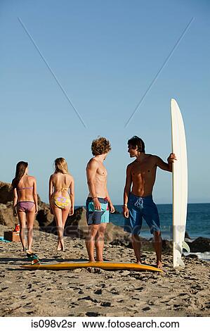 Stock Photography - Male friends checking out girls at the beach. Fotosearch