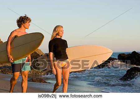 Stock Image - Surfer couple at the beach. Fotosearch