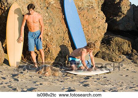 Stock Image - Surfers at the beach. Fotosearch