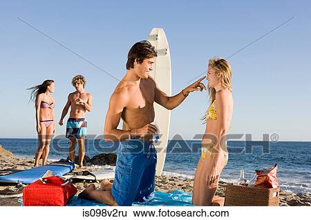 Stock Photograph - Young man applying sun lotion to girlfriend. Fotosearch