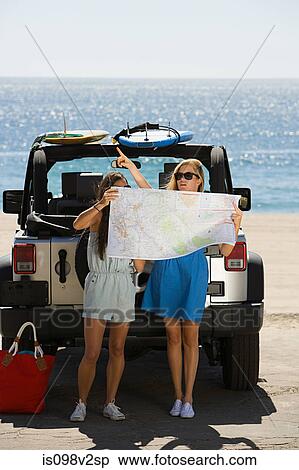 Stock Photography - Young women by vehicle, looking at map. Fotosearch
