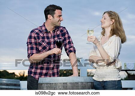 Stock Image - Couple tasting wine in vineyard. Fotosearch