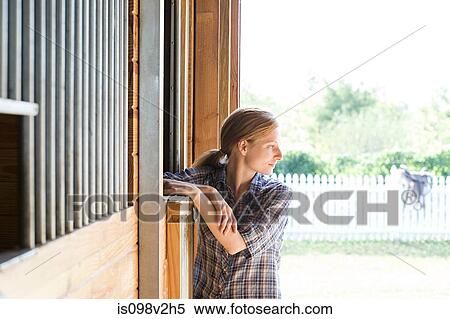 Stock Photography - Mid adult woman in stable, looking away. Fotosearch
